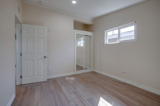 unfurnished bedroom with baseboards, visible vents, wood finished floors, a closet, and recessed lighting