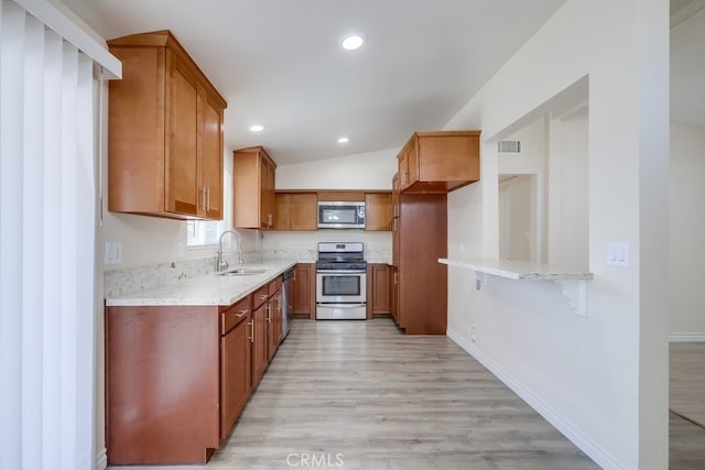 kitchen with brown cabinets, stainless steel appliances, visible vents, light wood-style floors, and a sink