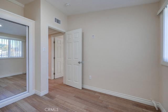 unfurnished bedroom featuring visible vents, light wood-style flooring, and baseboards