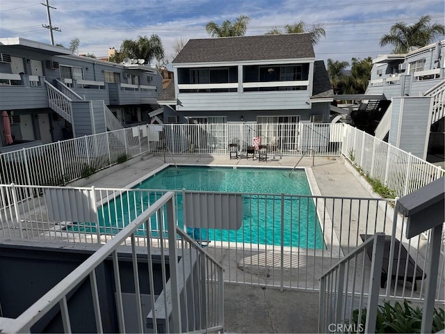 community pool featuring a patio area, a residential view, and fence