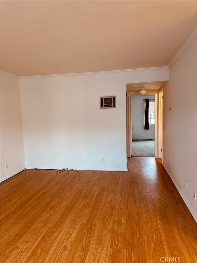 spare room with crown molding and wood finished floors