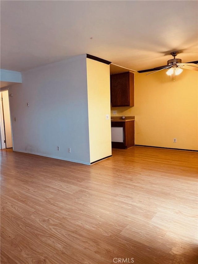 spare room featuring light wood-type flooring, ceiling fan, and baseboards