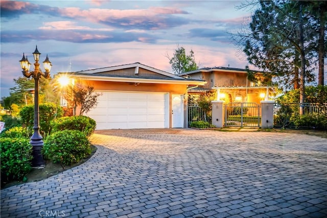 view of front of home featuring a fenced front yard, a garage, decorative driveway, a gate, and stucco siding