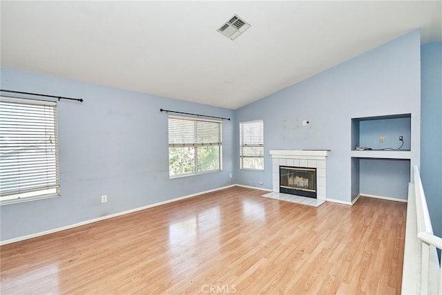 unfurnished living room with a fireplace, visible vents, vaulted ceiling, light wood-type flooring, and baseboards