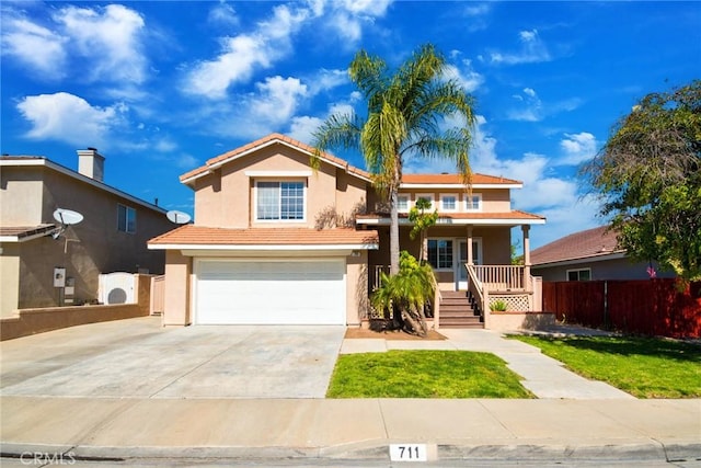 view of front of home featuring stucco siding, covered porch, fence, driveway, and a tiled roof