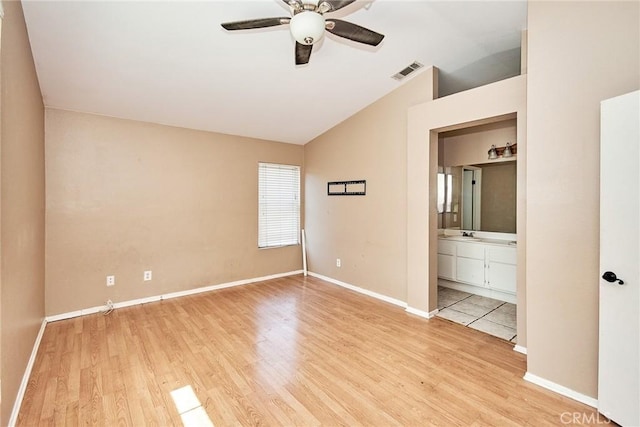 unfurnished bedroom with visible vents, light wood-style flooring, vaulted ceiling, ensuite bath, and baseboards