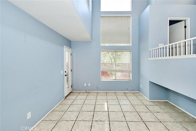 unfurnished room featuring tile patterned flooring, a high ceiling, and baseboards