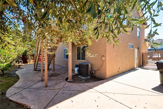 view of property exterior featuring central air condition unit, a patio area, and stucco siding