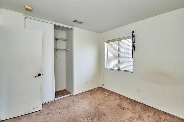 unfurnished bedroom featuring carpet floors, a closet, and visible vents