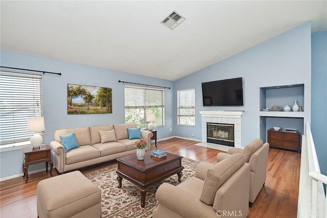 living room with lofted ceiling, visible vents, a fireplace, and wood finished floors