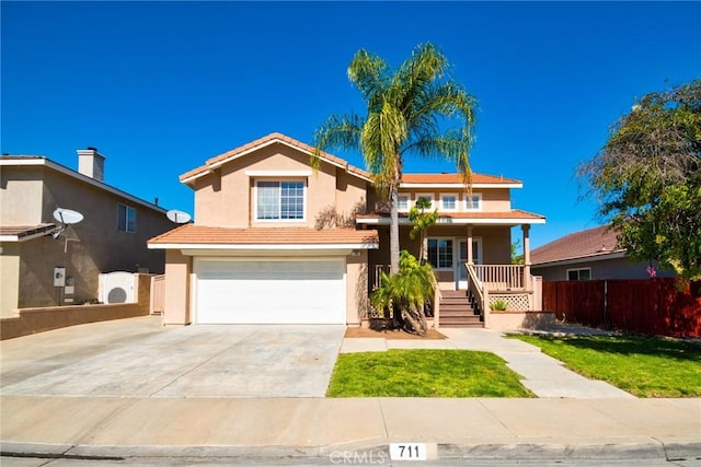 view of front of house featuring driveway, an attached garage, covered porch, fence, and stucco siding