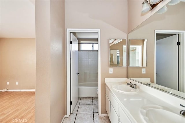 full bathroom featuring baseboards, a sink, toilet, and double vanity