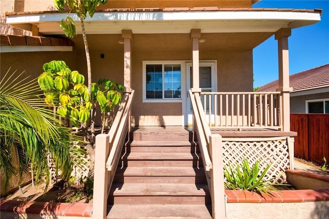 property entrance featuring covered porch and stucco siding