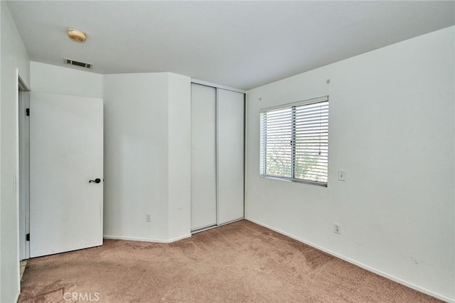 unfurnished bedroom with carpet, visible vents, and a closet