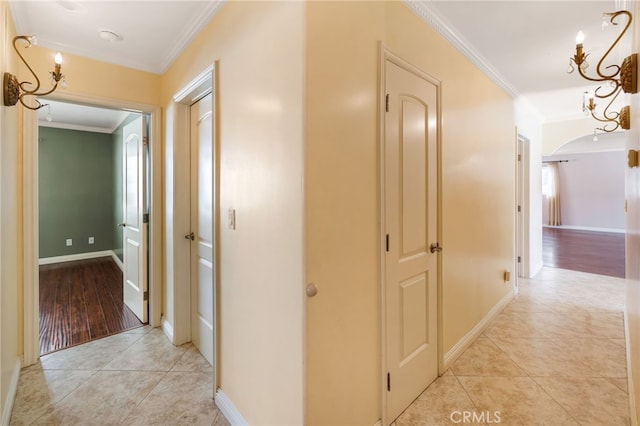 hall with light tile patterned floors, arched walkways, and crown molding