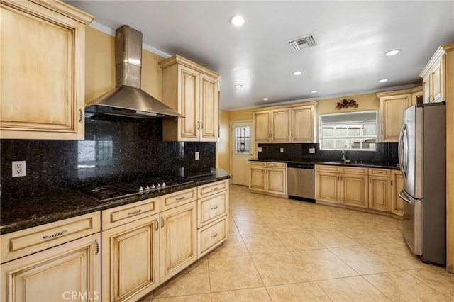 kitchen with light brown cabinets, visible vents, a sink, appliances with stainless steel finishes, and wall chimney exhaust hood