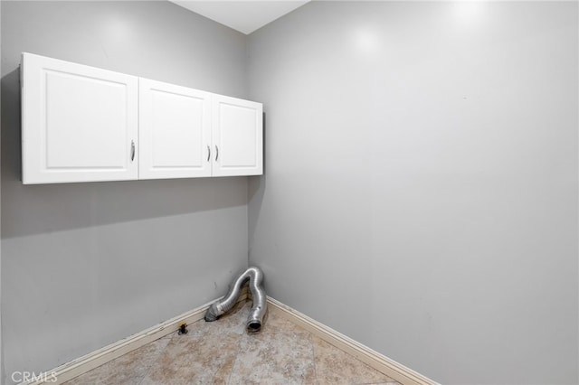 clothes washing area with baseboards and cabinet space