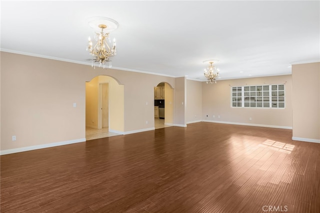 unfurnished room featuring baseboards, arched walkways, an inviting chandelier, and wood finished floors