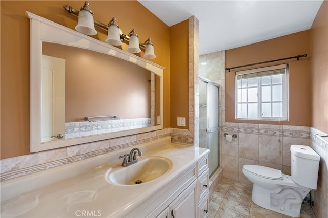 bathroom with a wainscoted wall, toilet, tile walls, a shower stall, and vanity