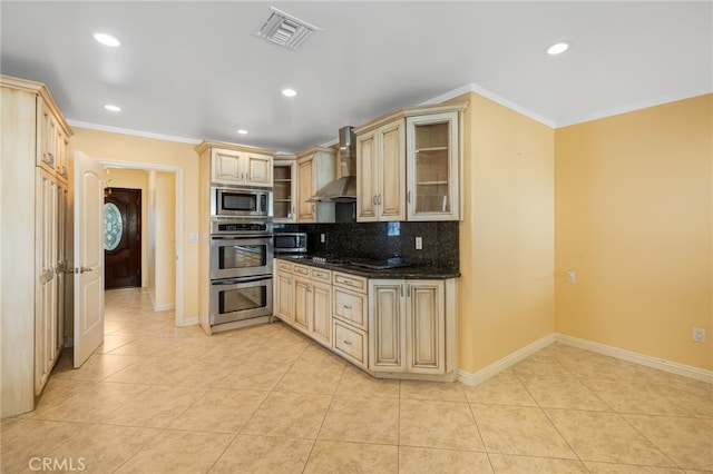 kitchen with visible vents, backsplash, wall chimney range hood, appliances with stainless steel finishes, and light tile patterned flooring