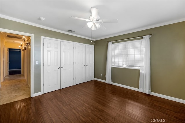 unfurnished bedroom featuring wood finished floors, visible vents, two closets, and baseboards