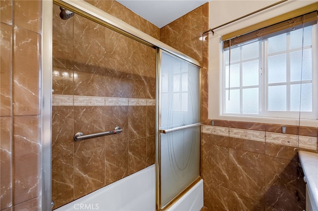 bathroom with combined bath / shower with glass door and tile walls