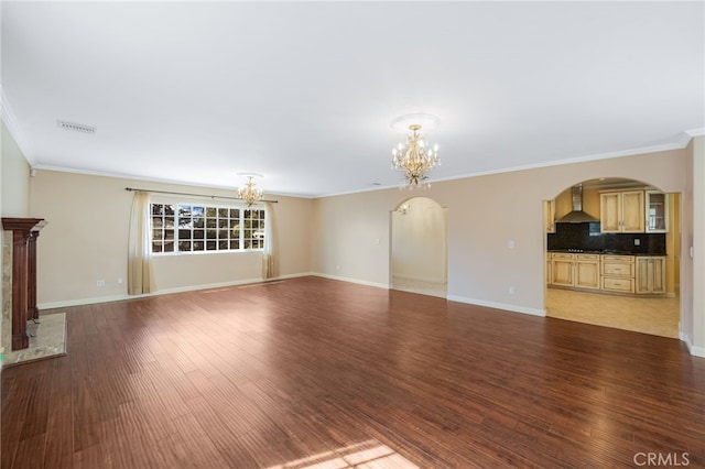 unfurnished living room with visible vents, ornamental molding, an inviting chandelier, wood finished floors, and arched walkways