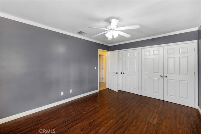 unfurnished bedroom featuring visible vents, baseboards, two closets, and wood finished floors