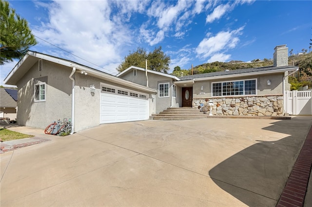 single story home with stucco siding, an attached garage, driveway, and fence