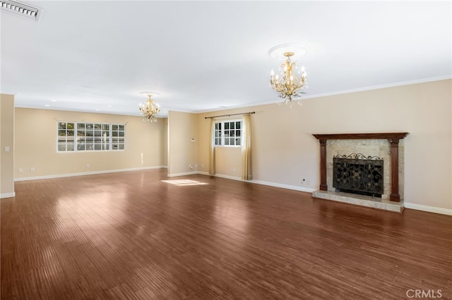 unfurnished living room featuring visible vents, a fireplace with raised hearth, baseboards, a chandelier, and wood finished floors