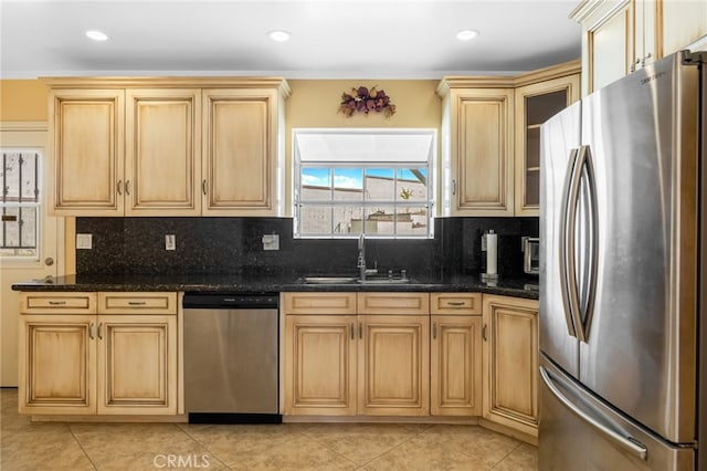 kitchen with decorative backsplash, light tile patterned flooring, appliances with stainless steel finishes, and a sink