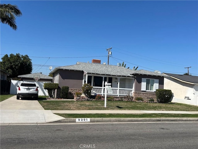 ranch-style home with covered porch, brick siding, a front lawn, and stucco siding