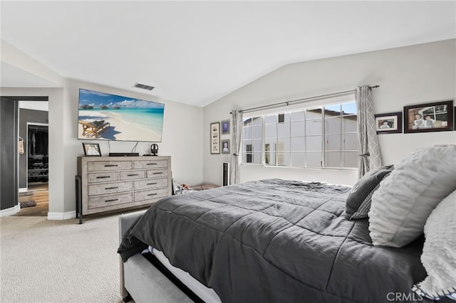 carpeted bedroom with visible vents, baseboards, a walk in closet, and lofted ceiling