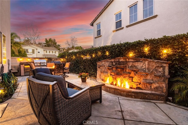 view of patio featuring outdoor dining space, an outdoor kitchen, and an outdoor stone fireplace