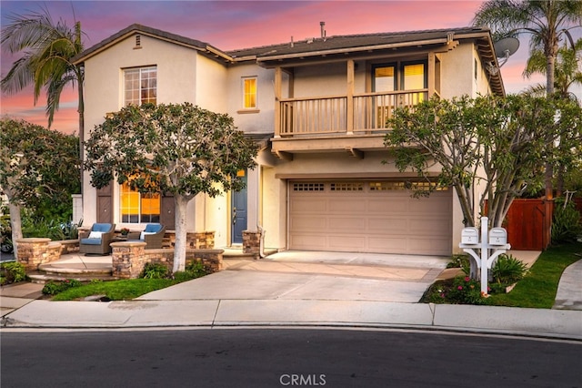 view of front of home with stucco siding, a balcony, a garage, and driveway