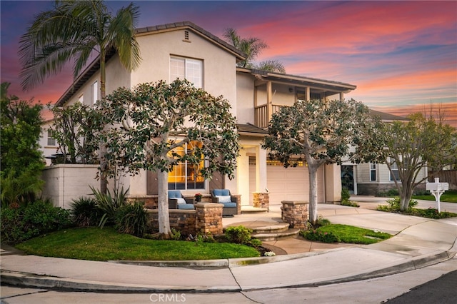 mediterranean / spanish-style house with a balcony, driveway, an attached garage, stucco siding, and outdoor lounge area