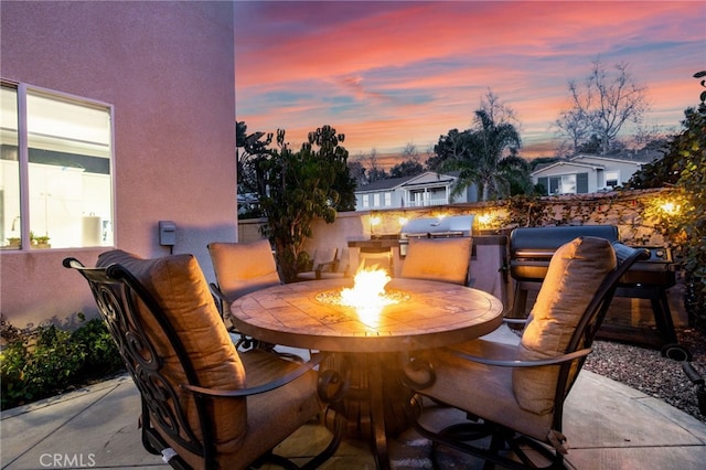 patio terrace at dusk featuring outdoor dining space and exterior kitchen