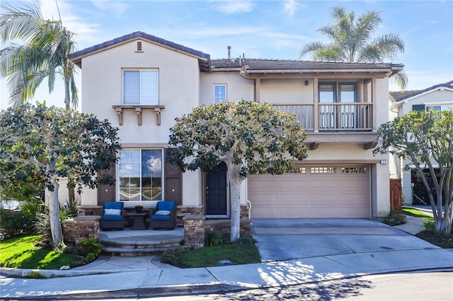 view of front of house featuring stucco siding, a garage, a balcony, and driveway