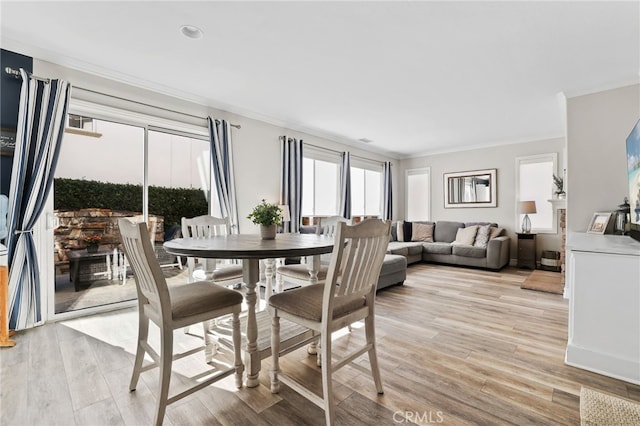 dining area featuring light wood-style flooring and ornamental molding