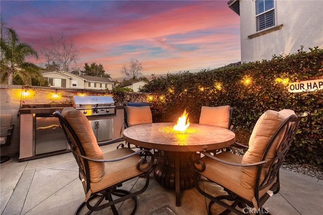 view of patio featuring fence, an outdoor kitchen, outdoor dining area, a fire pit, and grilling area