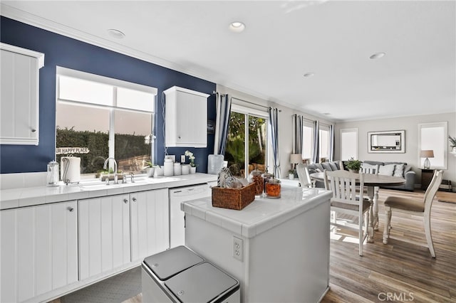 kitchen featuring wood finished floors, white cabinetry, tile counters, dishwasher, and open floor plan