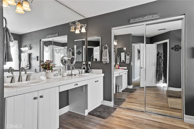 bathroom with double vanity, visible vents, wood finished floors, and a sink