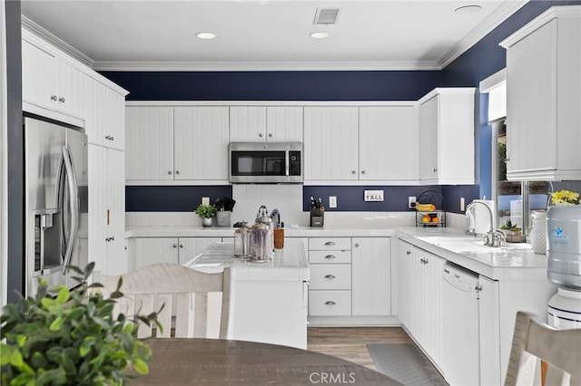 kitchen featuring visible vents, ornamental molding, stainless steel appliances, and a sink