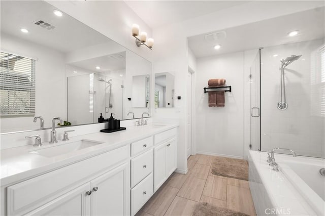 bathroom featuring tiled bath, a sink, visible vents, and a shower stall