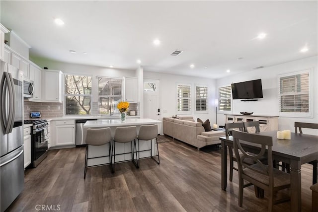 kitchen featuring dark wood-style floors, stainless steel appliances, a kitchen island, and a kitchen breakfast bar