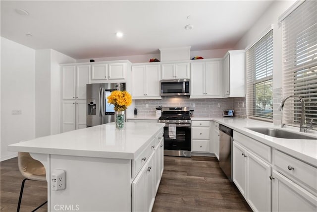 kitchen with decorative backsplash, dark wood-style floors, a kitchen island, appliances with stainless steel finishes, and a sink