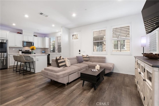 living area with dark wood-type flooring, recessed lighting, visible vents, and baseboards