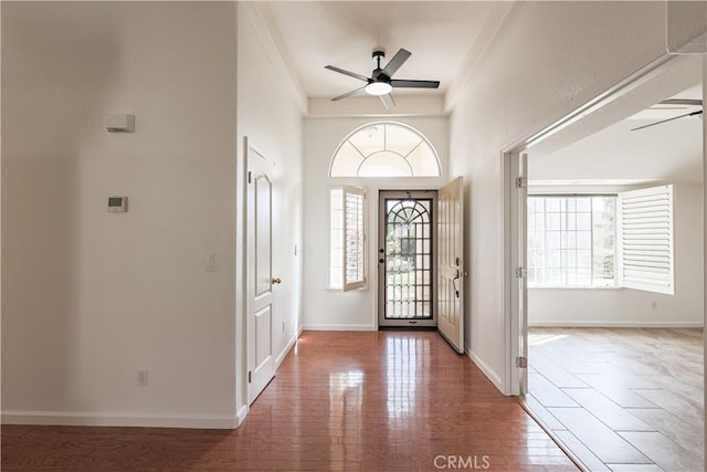 foyer with a ceiling fan, baseboards, and wood finished floors