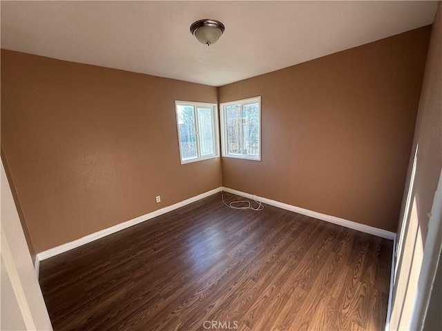 spare room with dark wood-style floors and baseboards