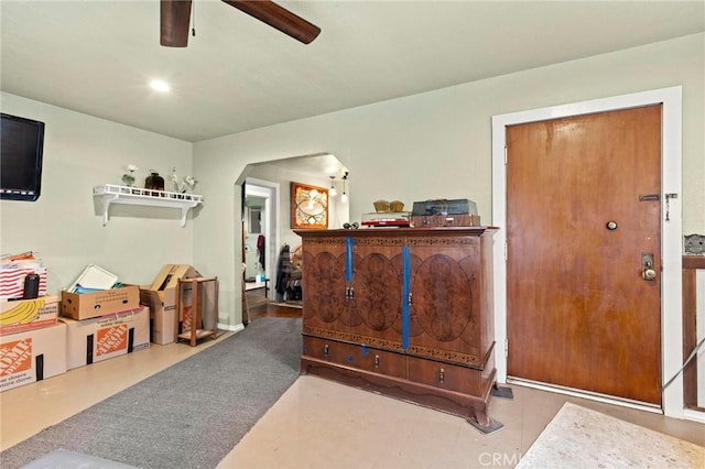 recreation room with arched walkways and a ceiling fan